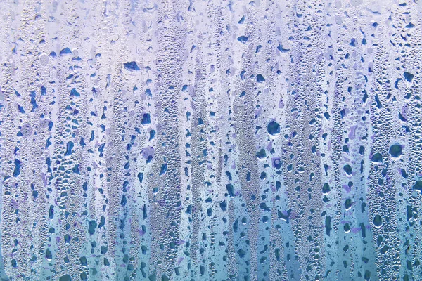 Islak şeffaf yüzeyde yağmur damlaları var. Sulu cam..
