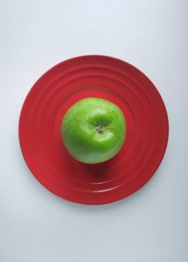 Kırmızı seramik tabakta yeşil elma