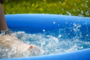 Küçük kız oynarken ve yaz aylarında açık yüzme havuzunda su püskürtme.