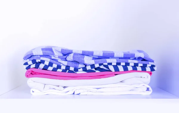 Stapel Van Verschillende Kleurrijke Kleren Wit Houten Kast Plank — Stockfoto