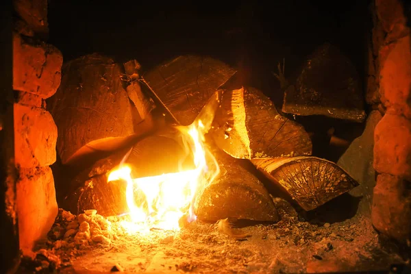 Warm light of a burning bright fire in a fireplace in old Russian stove. Flame and firewood background. Detail of interior.