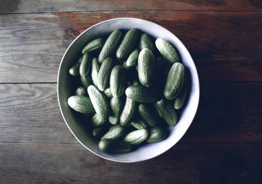 Tahta arka planda büyük bir fincanda taze salatalıklar.