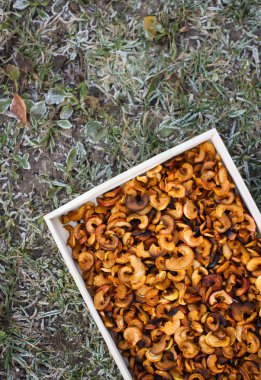 Slices of dried organic apples in a wooden tray close up.