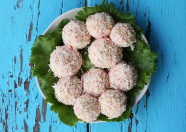 Mavi ahşap masa arkasında salatalı yengeç peyniri topları..