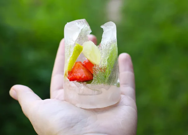 Cubo de hielo derretido con hojas de fresa, limón y menta verde fresca —  Fotos de Stock