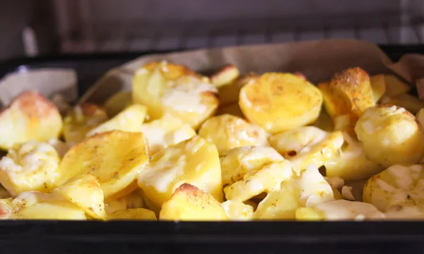 Raw potatoes prepared for baking with flavorings on tray.