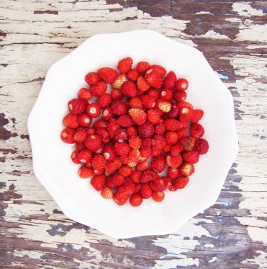 Olgun kırmızı çilekler, açık havada tahta bir masada kapanıyor.