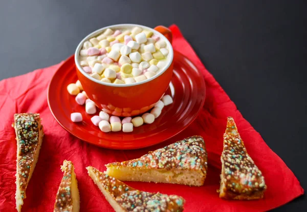 Cocoa drink with colorful small marshmallows on red background