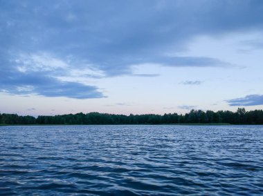 Letonya, Doğu Avrupa 'da akşam vakti göl yüzeyinde. Su ve ormanlı manzara.