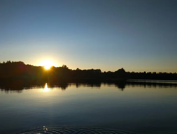 Calm lake surface at evening in Latvia, East Europe. summer sunset landscape with water and forest.