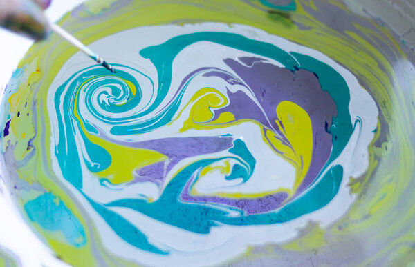 Процесс создания эбру живописи красочными красками, бумагой и деревянной палкой. Яркий абстрактный рисунок в воде
.