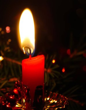 Yanan kırmızı mum alevinin sıcak ışığı.