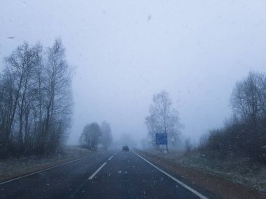 Asfalt yol ve gökyüzündeki bulutlar. Kışın kar yağışı.