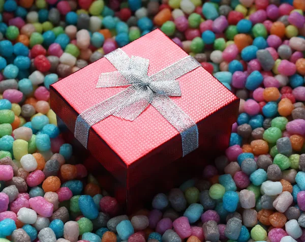 Red gift box on colorful corn chips — Stock Photo, Image