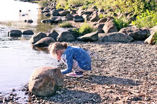 春には川沿いの小さな石で遊ぶ愛らしい少女 — ストック写真