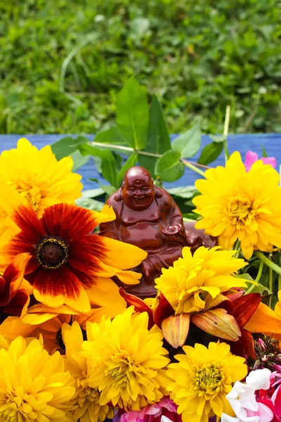 Bouquet de fleurs d'été lumineuses et bouddha en céramique figure reine sur des planches de bois colorées . — Photo