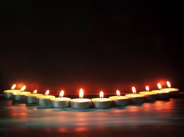 Koyu arkaplanda mumlar yakılıyor.