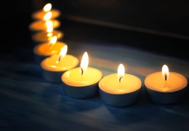 Koyu arkaplanda mumlar yakılıyor.