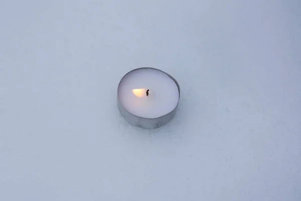 Burning tea light candle on the snow.