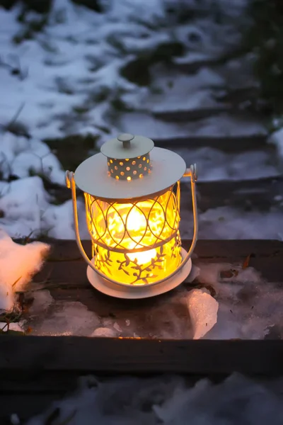 Декоративний ліхтар з палаючою свічкою на старих дерев'яних сходах в зимовому парку — стокове фото
