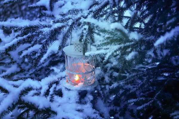 Decorative Christmas lantern with burning candle hanging on snow-covered fir- tree branch in a winter park. New year festive card, poster, postcard design. — 스톡 사진