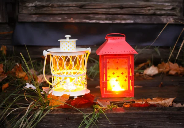Декоративный фонарь с горящей свечой в осеннем парке вечером . — стоковое фото