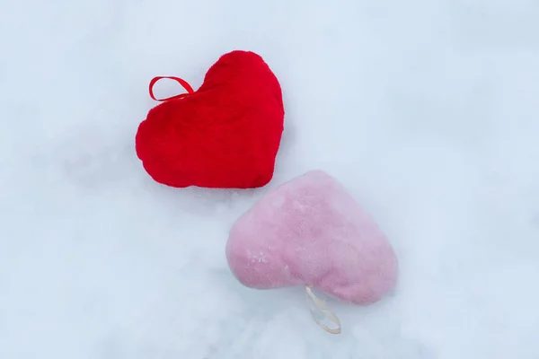 Rosa y rojo corazones decorativos de felpa en la nieve — Foto de Stock