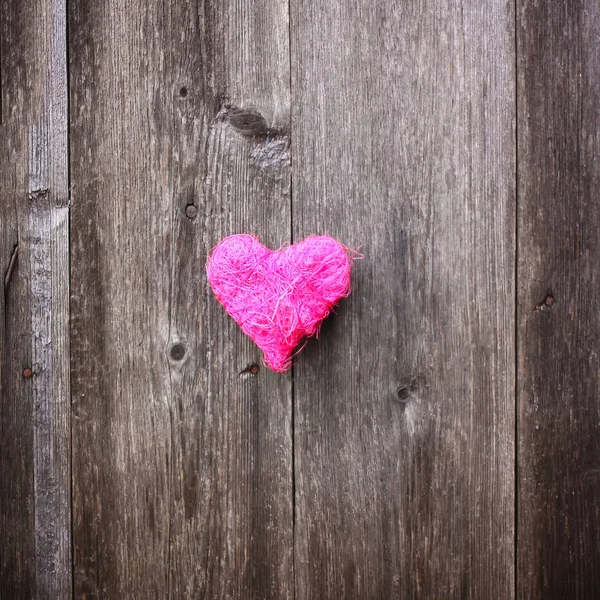 Decorative small heart on wooden old weathered background.