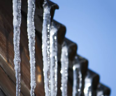 Çatıda asılı parlak şeffaf buz sarkıtları.