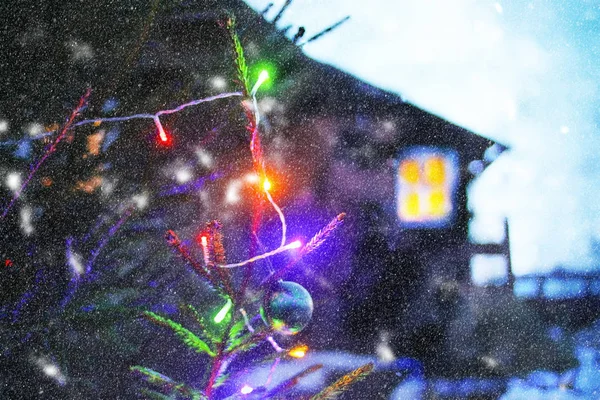 Abete decorato all'aperto su sfondo casa rurale. Vacanze invernali sfondo festivo . — Foto Stock