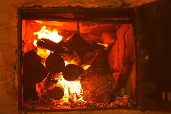 Warm licht van een brandende felle brand in een open haard in de oude Russische kachel. Vlam en brandhout achtergrond. Detail van het interieur. — Stockfoto