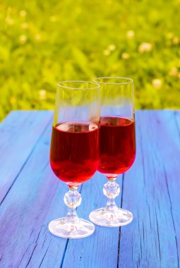 Yazın kırsal alanda mavi tahtalarda ev yapımı kırmızı asmalı iki bardak..