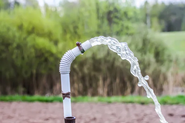 Pulvérisation d'eau transparente dans un tuyau à l'extérieur à la source . — Photo