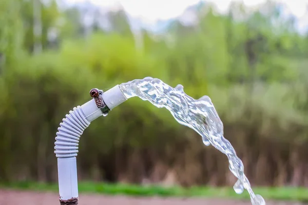 Transparent water spray in a hose outdoors at spring. — Stock Photo, Image