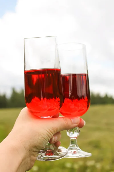 夏天，在乡间的农场院子里，一只手拿着自制的红色葡萄藤酒杯. — 图库照片