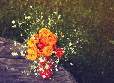 Ahşap bir masanın arka planında vazoda duran güzel bir buket çiçek.