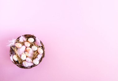 Geleneksel dekorlu Paskalya kompozisyonu. Hasır sepette küçük renkli yumurtalar ve yumuşak tüyler..