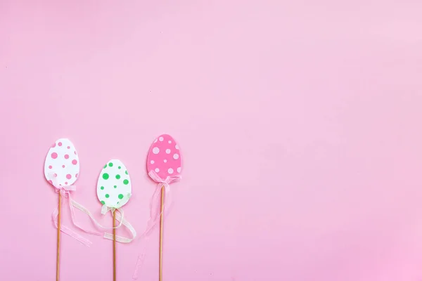 Пасхальная композиция с традиционным декором. Маленькие декоративные красочные яйца на деревянных палочках на мягком розовом фоне . — стоковое фото