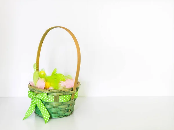 Composição de Páscoa com decoração tradicional. Pequenos ovos coloridos decorativos e penas macias em uma cesta . — Fotografia de Stock
