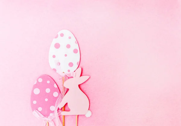 Paascompositie met traditionele inrichting. Houten decoratieve ei en konijn figuren op zachte licht roze achtergrond. — Stockfoto