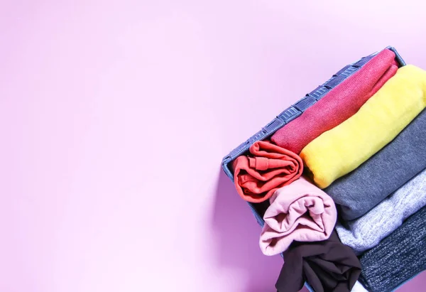 Vêtements colorés rangement vertical dans la garde-robe à domicile. Vêtements en boîte textile sur fond rose doux . — Photo