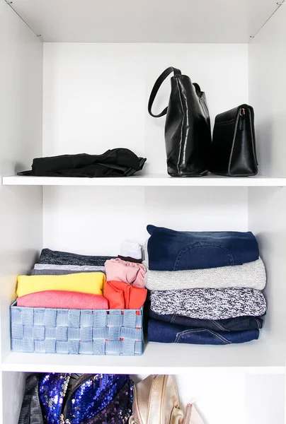 Clasificación de ropa en el armario del hogar. Diferentes prendas de vestir y accesorios de bolsa en estante blanco . —  Fotos de Stock