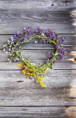 Eski ahşap arka planda yabani çiçeklerin çelengi.