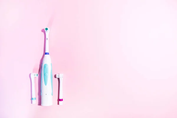 Due spazzolini elettrici su uno sfondo rosa chiaro morbido — Foto Stock