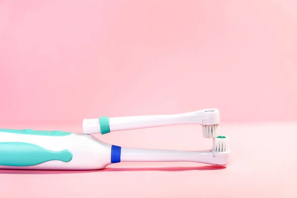 Дві електричні зубні щітки на м'якому світло-рожевому фоні — стокове фото