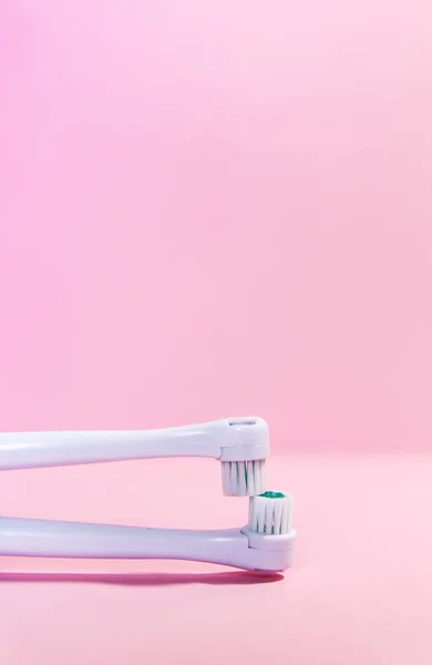 Två elektriska tandborstar på en mjuk ljusrosa bakgrund — Stockfoto