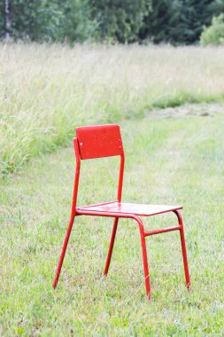 Kırsal kesimde yeşil çayırda kırmızı sandalye.