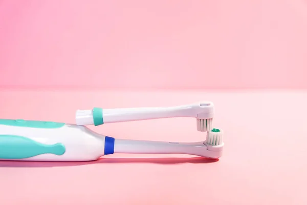 Två elektriska tandborstar på en mjuk ljusrosa bakgrund — Stockfoto