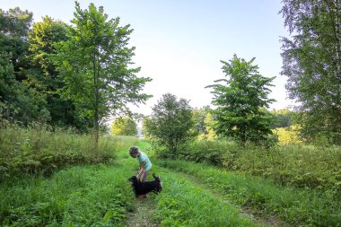 Küçük kız köpeğiyle ormanda yürüyor.
