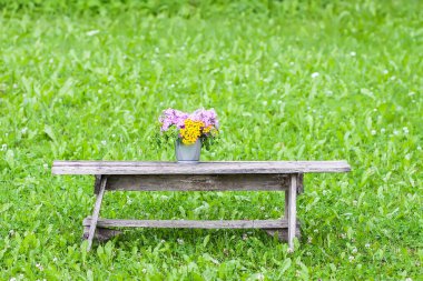 Güzel bir buket kır çiçeği ahşap bankta yaz mevsiminde kırsal alanda doğa arka planında.